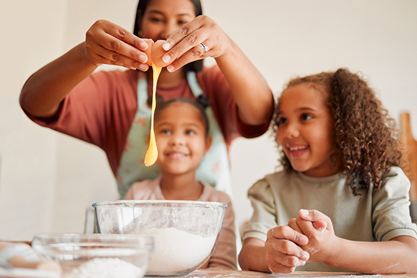 Females only, happy mixed race family of three cooking in a messy kitchen together. Loving black si.